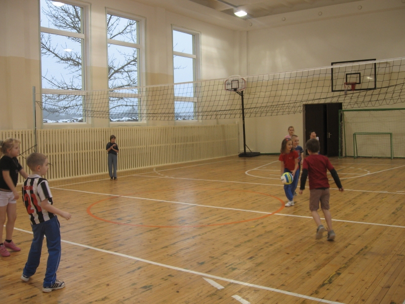 Mazie meņģelieši renovētajā sporta zālē spēlē tautasbumbu.